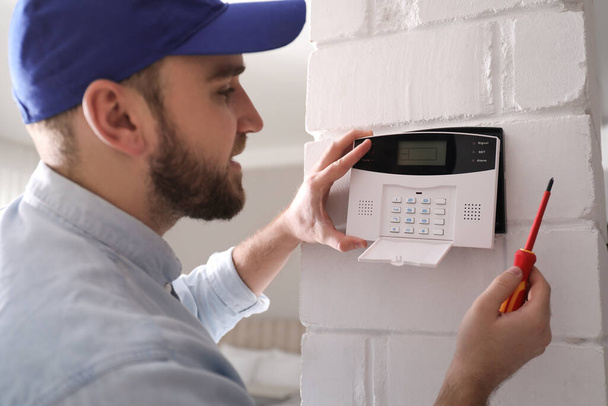 Man installing home security system on white wall in room - Foto, Imagem