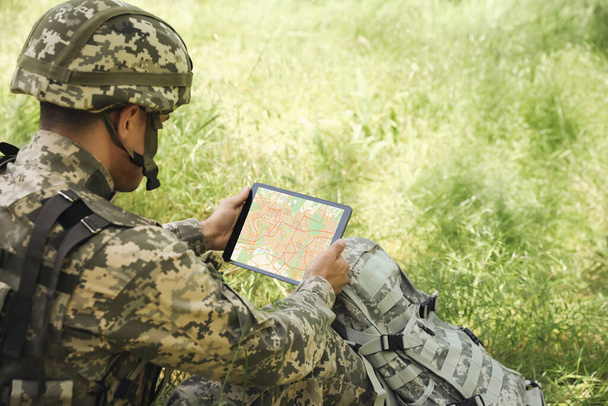 Soldier with backpack using tablet in forest - Foto, Bild