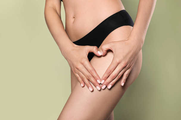 Closeup view of slim woman in underwear showing heart on light green background. Cellulite problem concept - Foto, afbeelding