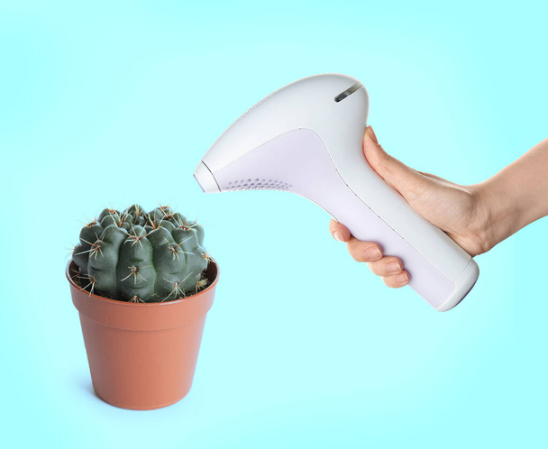 Hair removal concept. Cactus and woman holding modern photoepilator on turquoise background, closeup - Фото, зображення