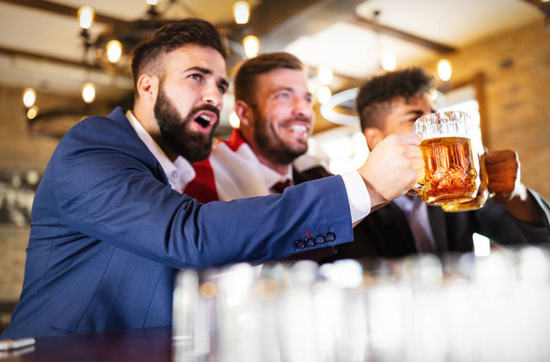 Handsome business men in pub cheering for a sporting event - Foto, Bild