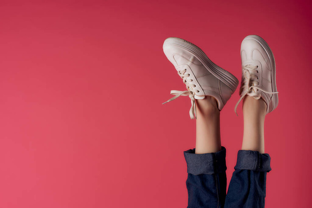 female legs upside down in white sneakers pink background fashion - Foto, afbeelding