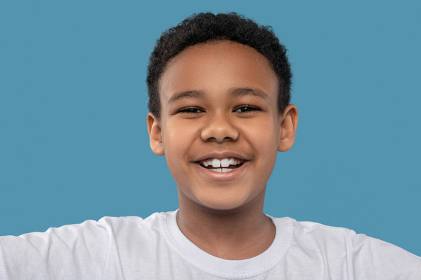 Fröhlicher afrikanisch-amerikanischer Junge mit zahmem Lächeln - Foto, Bild