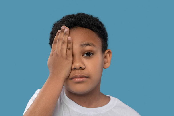 Chłopiec zakrywający jedno oko dłonią - Zdjęcie, obraz