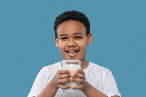 Garçon drôle avec verre de lait montrant la langue - Photo, image