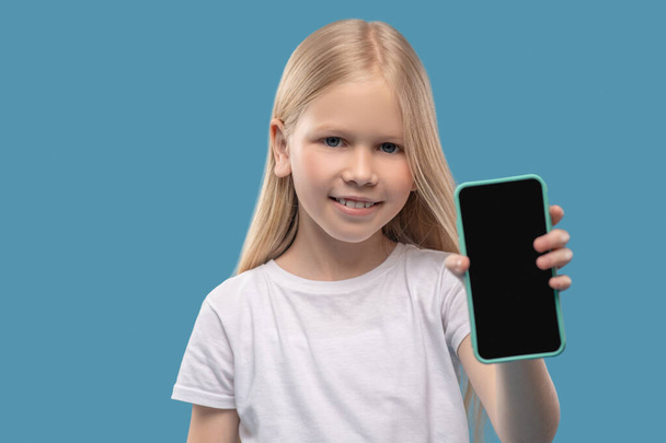 Маленька усміхнена дівчинка показує екран смартфона
 - Фото, зображення