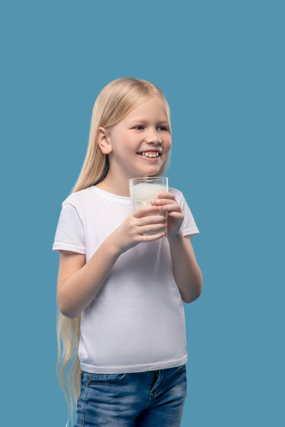 Smiling girl standing with glass of milk - Photo, Image