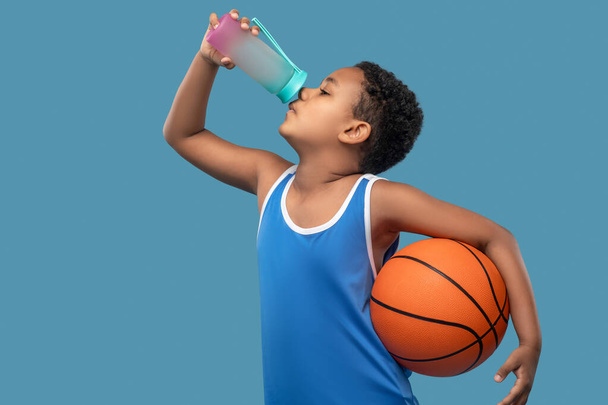 Ragazzo con palla che beve acqua dalla bottiglia sportiva - Foto, immagini