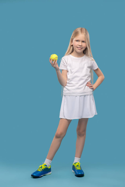 Mädchen in weißer Sportbekleidung mit Tennisball - Foto, Bild