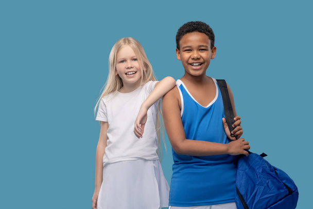 Счастливые дети в спортивной одежде стоят на синем фоне - Фото, изображение