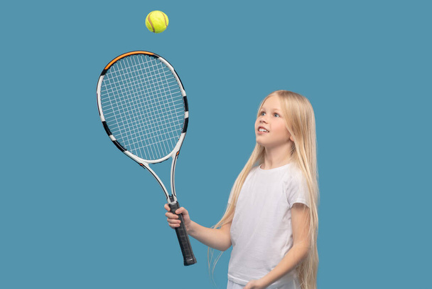 Girl hitting ball with tennis racket - Fotó, kép