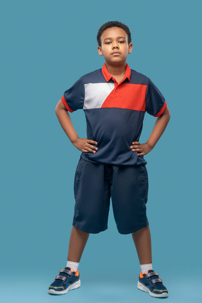 Garçon à la peau foncée en vêtements de sport sur fond bleu - Photo, image