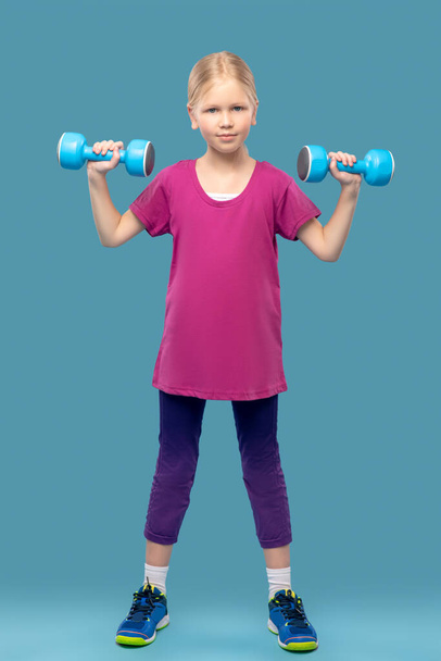 Girl in sportswear with dumbbells in hands - Valokuva, kuva