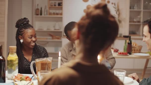 Heureux homme afro-américain assis avec bébé fils mignon sur ses genoux à la table du dîner tout en célébrant des vacances à la maison avec la compagnie d'amis multiethniques - Séquence, vidéo