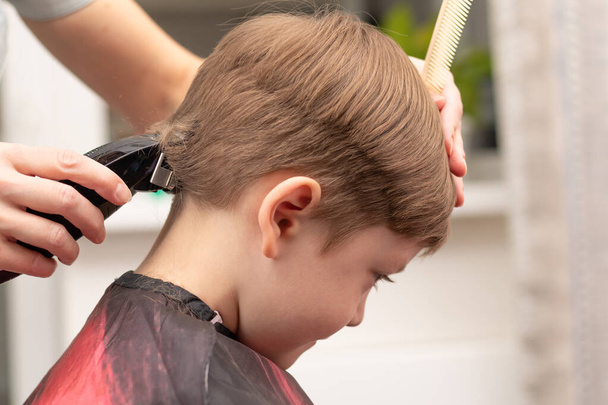 jovem mãe cabeleireiro corta seu menino em casa com cortador de cabelo durante a quarentena. foco seletivo. retrato - Foto, Imagem