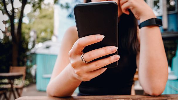young woman or teenage girl hand using mobile phone in cafe outdoor - Foto, imagen