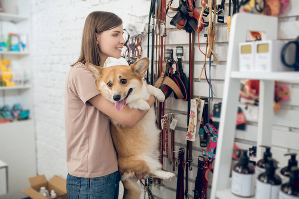 A happy girl and her cute dog in a pet store - 写真・画像