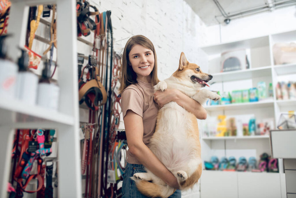 A happy girl and her cute dog in a pet store - Zdjęcie, obraz