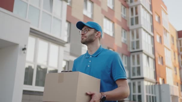 Een bezorger brengt een pakket naar klanten in een woonwijk. Boodschappenbezorging en online winkelen - Video