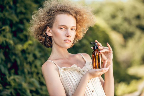 Pretty woman holding a bottle of essential organic oil in hands - Foto, immagini