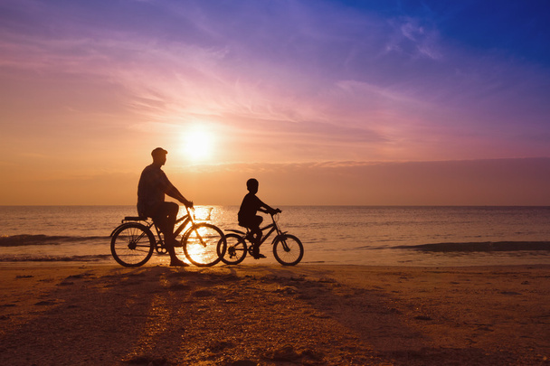 pai e filho na praia ao pôr do sol, silhueta da família Biker
  - Foto, Imagem