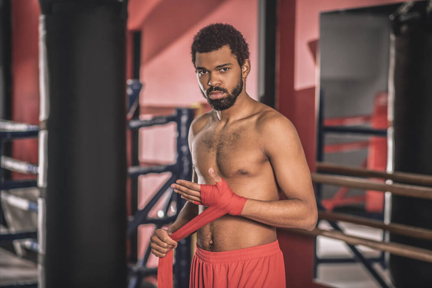 トレーニングの前に彼の手に包帯を入力するアフリカ系アメリカ人キックボクサー - 写真・画像