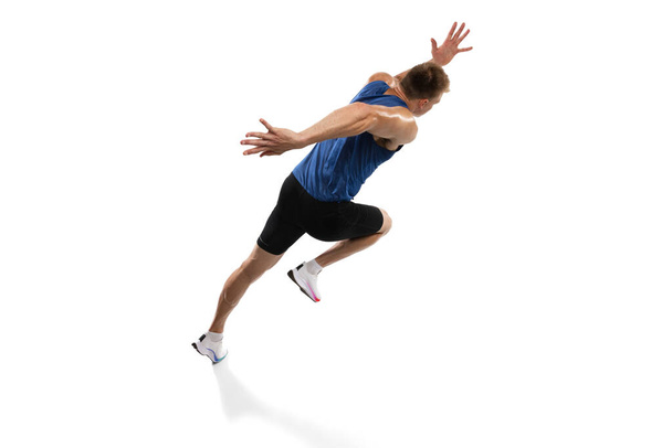 Caucasian professional male athlete, runner training isolated on white studio background. Muscular, sportive man. Concept of action, motion, youth, healthy lifestyle. Copyspace for ad. - Photo, Image