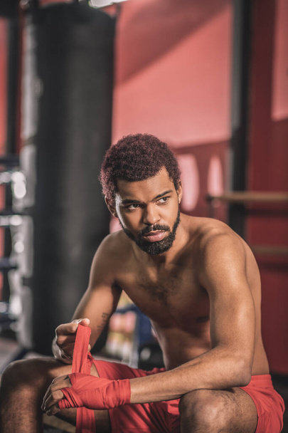 Kickboxer afro-américain tapant un bandage sur sa main avant l'entraînement - Photo, image