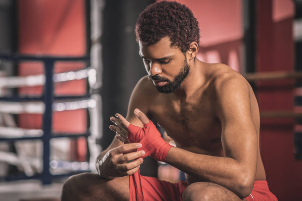Kickboxer afro-américain tapant un bandage sur sa main avant l'entraînement - Photo, image