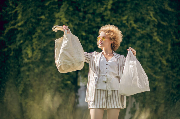 Curly haired young woman with bags in hands - Photo, image