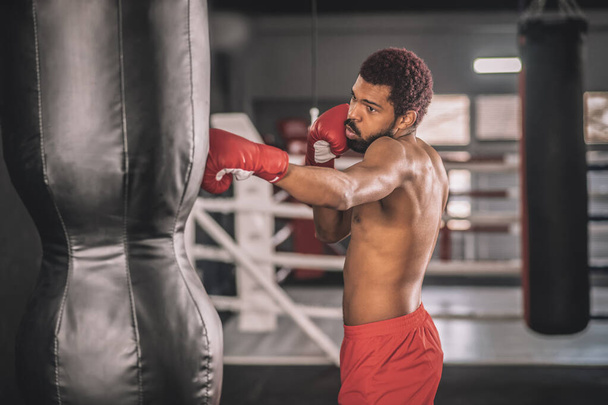 Afroamerikanischer Kickboxer trainiert in einem Fitnessstudio an seinen Tritten - Foto, Bild