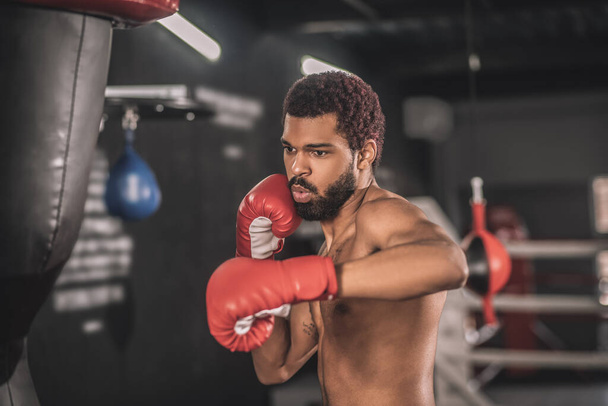 Young dark-skinned kickboxer having a workout in a gym - Фото, изображение