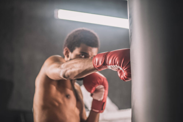 kickboxer de pele escura tendo um treino em um ginásio e olhando envolvido - Foto, Imagem