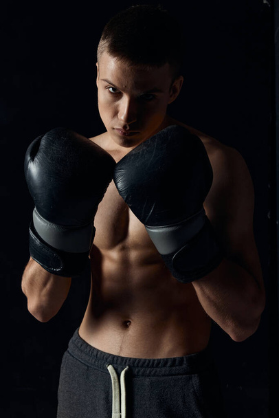 Siyah eldivenli boksör arka planda şişirilmiş gövde vücut geliştirici fitness - Fotoğraf, Görsel
