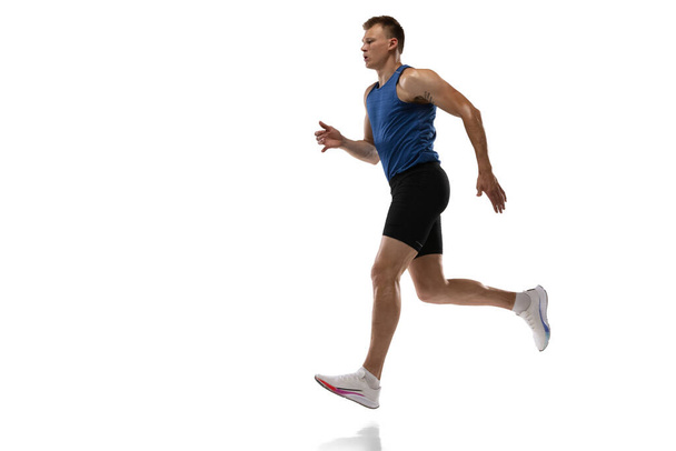 Caucasian professional male athlete, runner training isolated on white studio background. Muscular, sportive man. Concept of action, motion, youth, healthy lifestyle. Copyspace for ad. - Photo, Image