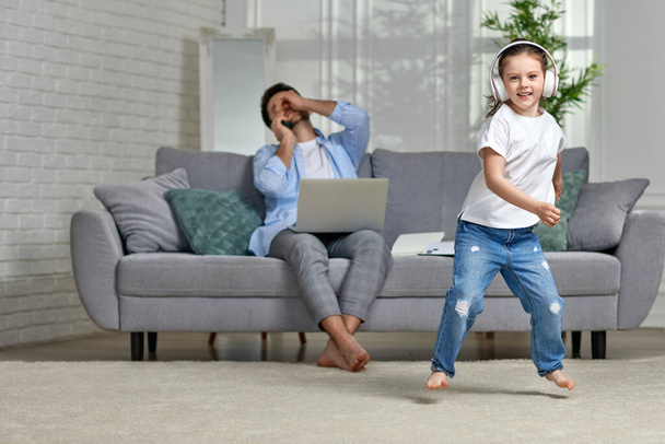 kid dancing and busy dad working with laptop at home - Photo, image
