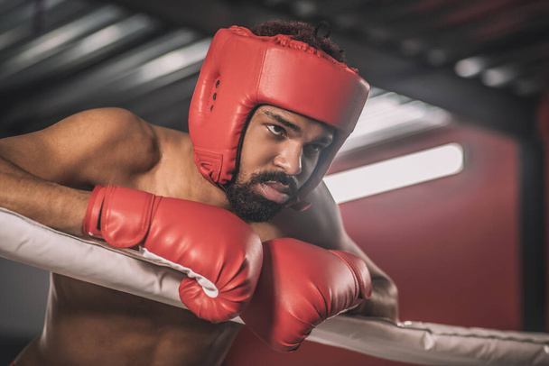 Kickboxer dalla pelle scura in un orlo rosso a riposo dopo la lotta - Foto, immagini