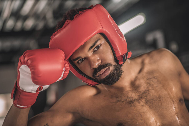 Kickboxer de piel oscura en un dobladillo rojo que parece cansado después de la pelea - Foto, Imagen