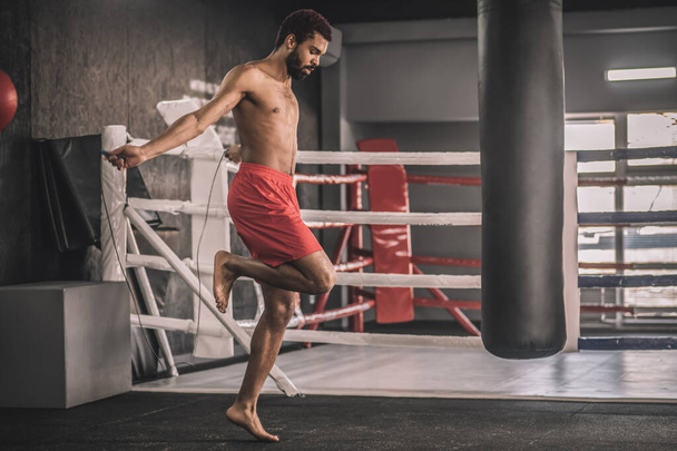 Hombre en pantalones cortos rojos saltando antes del entrenamiento - Foto, Imagen