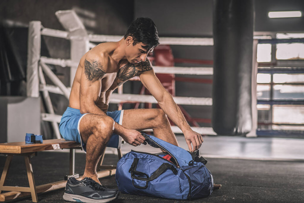 Muscular construir hombre sentado en un vestuario en un gimnasio - Foto, imagen
