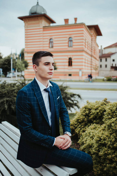 A caucasian young businessman in a suit and tie sitting outdoor. - Фото, зображення