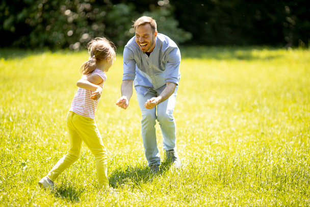 Vater jagt seine süße kleine Tochter beim Spielen im Park - Foto, Bild