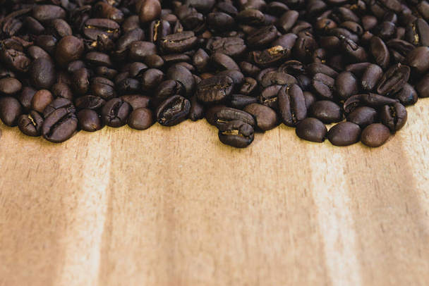 The pile of coffee beans on a wooden background - 写真・画像
