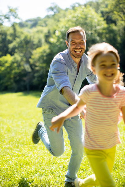Padre persiguiendo a su linda hijita mientras juega en el parque - Foto, imagen