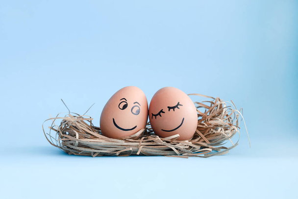 Brown egg with funny angel face in a nest - 写真・画像