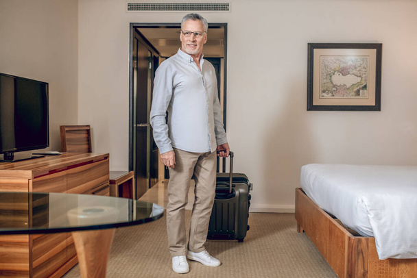 Šedovlasý sebevědomý muž v hotelovém pokoji - Fotografie, Obrázek