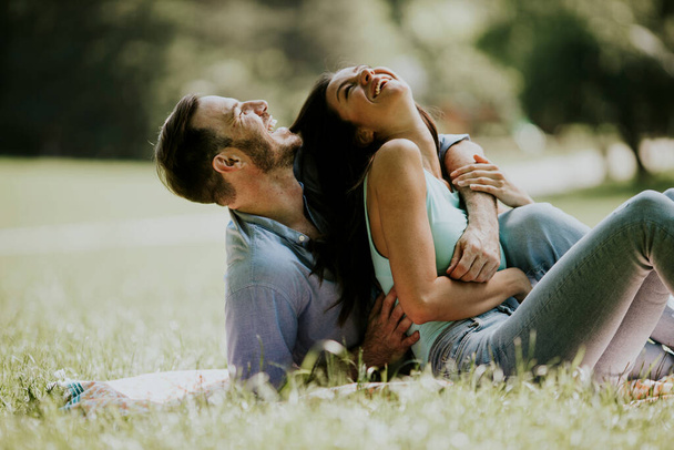 Affectionate young couple sitting on the green grass at the park - Photo, Image