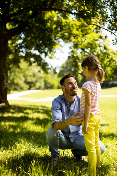 Батько з милою маленькою донькою розважається на траві в парку
 - Фото, зображення