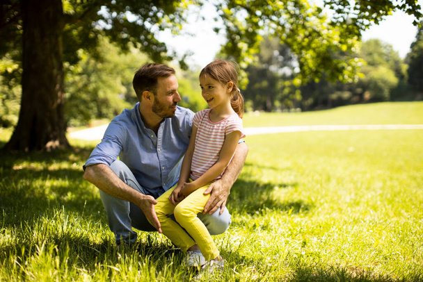Отец с милой маленькой дочкой веселится на траве в парке - Фото, изображение