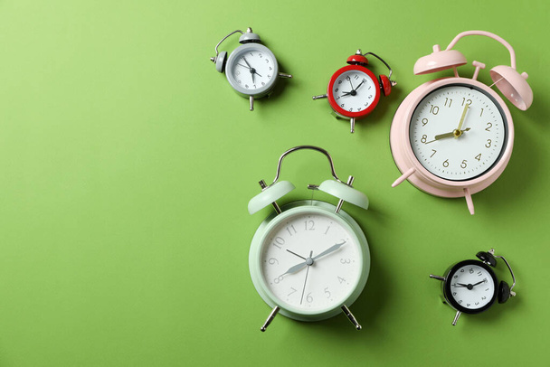 Different multicolor alarm clocks on green background - Foto, afbeelding